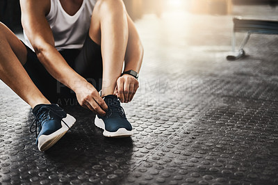 Buy stock photo Cropped shot of a man tying his shoelaces in a gym