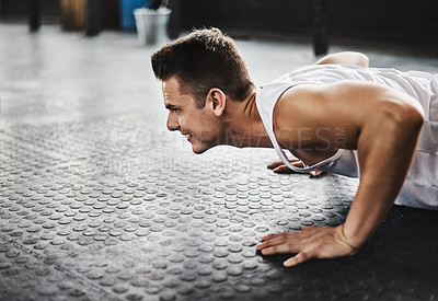 Buy stock photo Shot of a young man doing pushups in a gym