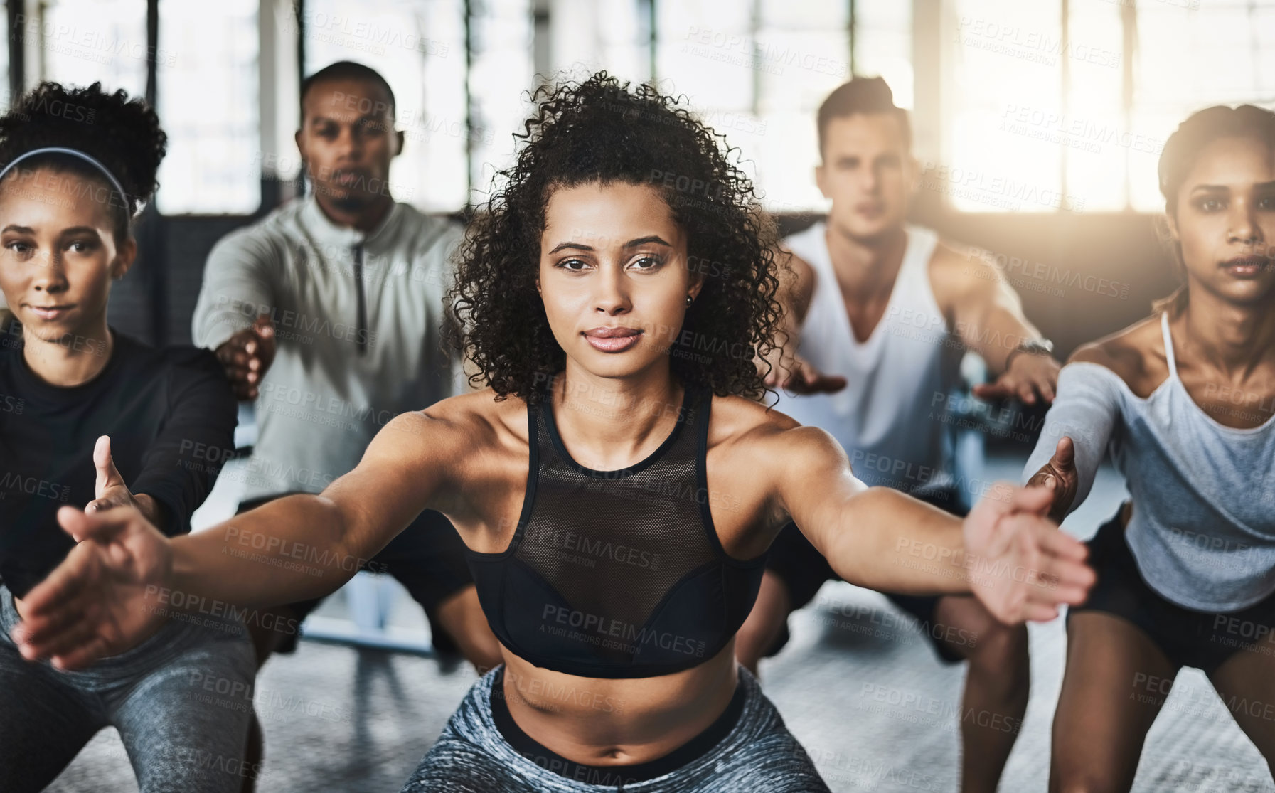 Buy stock photo Shot of a group of young people doing squats together during their workout in a gym