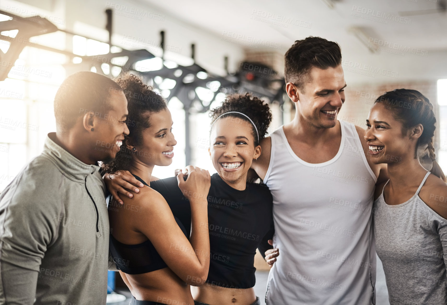 Buy stock photo Shot of a group of happy young people working out together in a gym