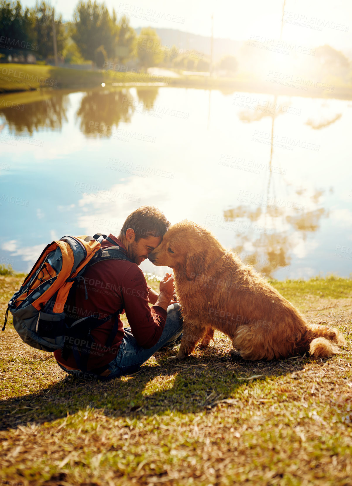 Buy stock photo Full length shot of a handsome young man and his dog sitting by a lake in the park