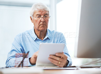 Buy stock photo Cropped shot of a handsome senior businessman working on a tablet at home