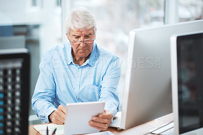 Buy stock photo Cropped shot of a handsome senior businessman working on a tablet at home