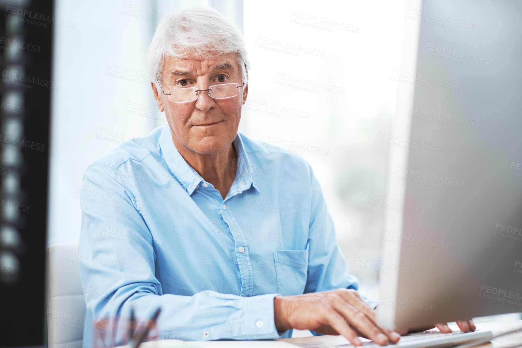 Buy stock photo Cropped portrait of a handsome senior businessman working on his computer at home