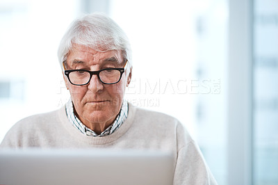 Buy stock photo Cropped shot of a handsome senior businessman working on his laptop at home