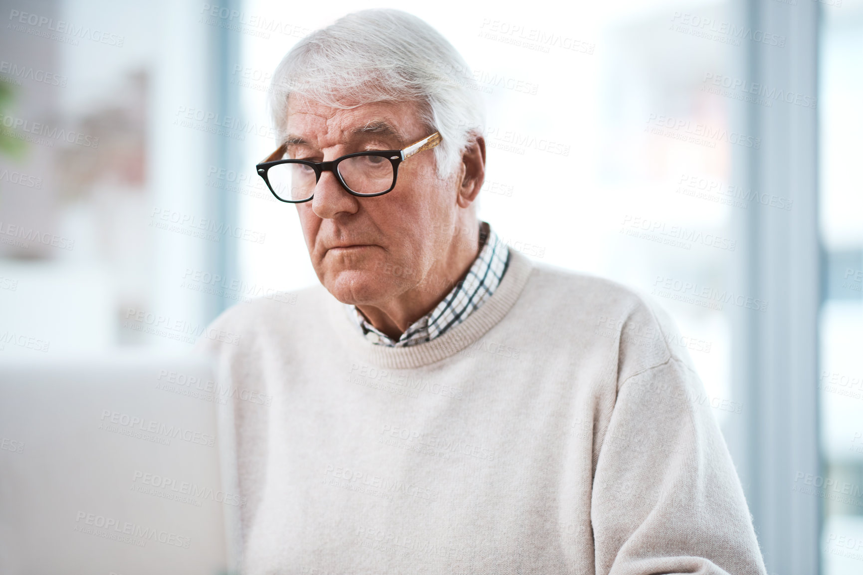 Buy stock photo Cropped shot of a handsome senior businessman working on his laptop at home