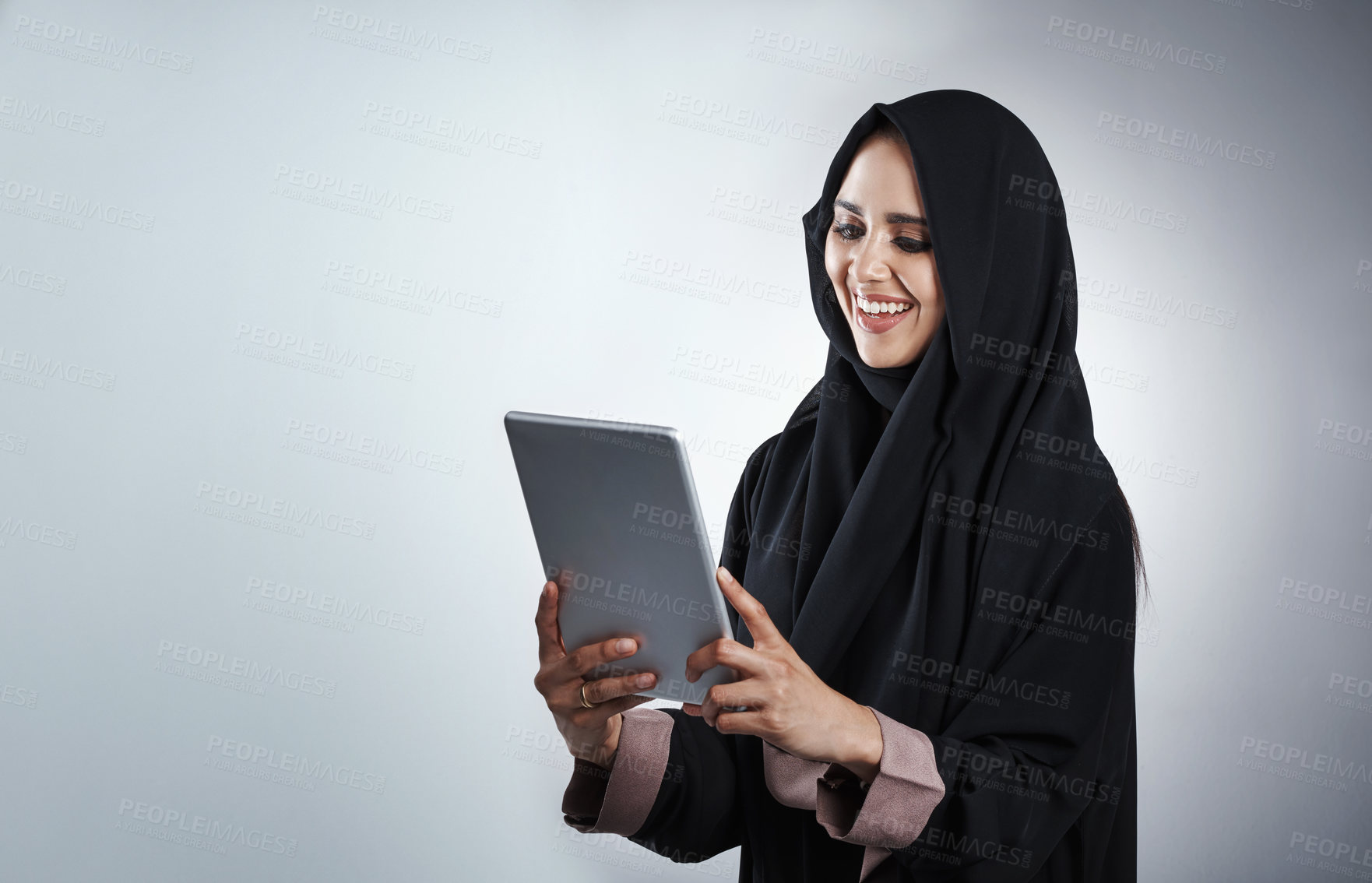 Buy stock photo Cropped shot of an attractive young businesswoman using her tablet while standing against a grey background