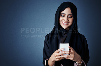 Buy stock photo Cropped shot of an attractive young businesswoman sending a text while standing against a dark background