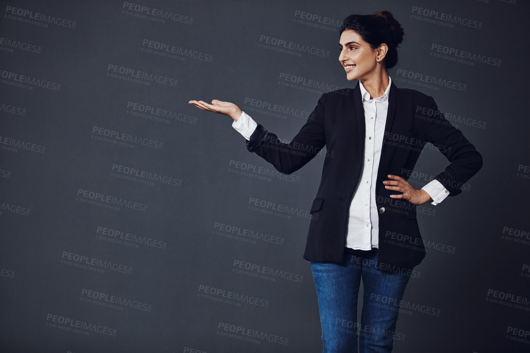 Buy stock photo Studio shot of an attractive young businesswoman pointing at copy space against a dark background