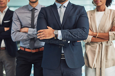 Buy stock photo Shot of a group of unrecognizable businesspeople standing with their arms folded inside of the office at work during the day