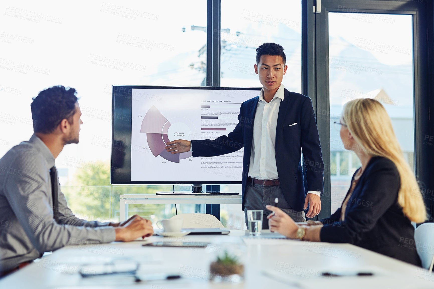 Buy stock photo Shot of a young businessman delivering a presentation to his colleagues in the boardroom of a modern office