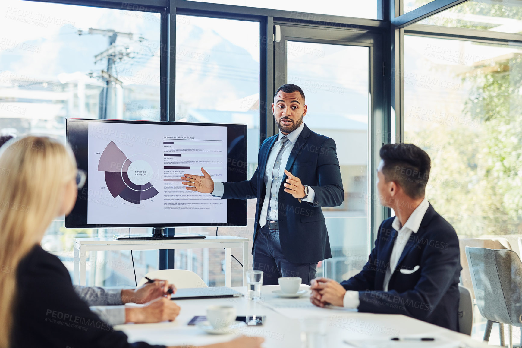 Buy stock photo Shot of a young businessman delivering a presentation to his colleagues in the boardroom of a modern office