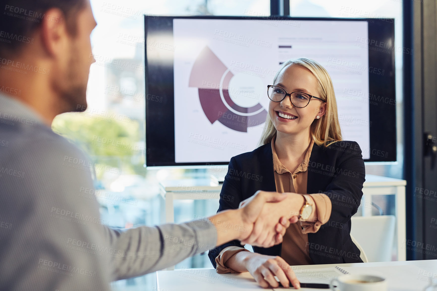Buy stock photo Shot of a young businesswoman and businessman shaking hands during a meeting in a modern office