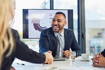 Buy stock photo Shot of a young businessman and businesswoman shaking hands during a meeting in a modern office