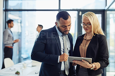 Buy stock photo Shot of a young businessman and businesswoman using a digital tablet together in the boardroom of a modern office