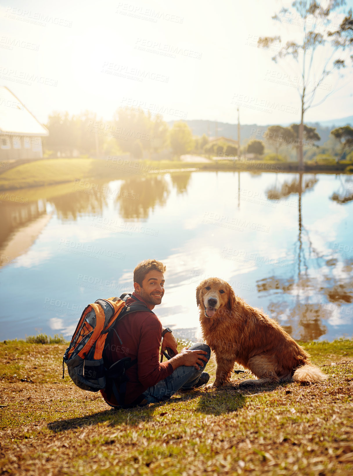 Buy stock photo Full length portrait of a handsome young man and his dog sitting by a lake in the park