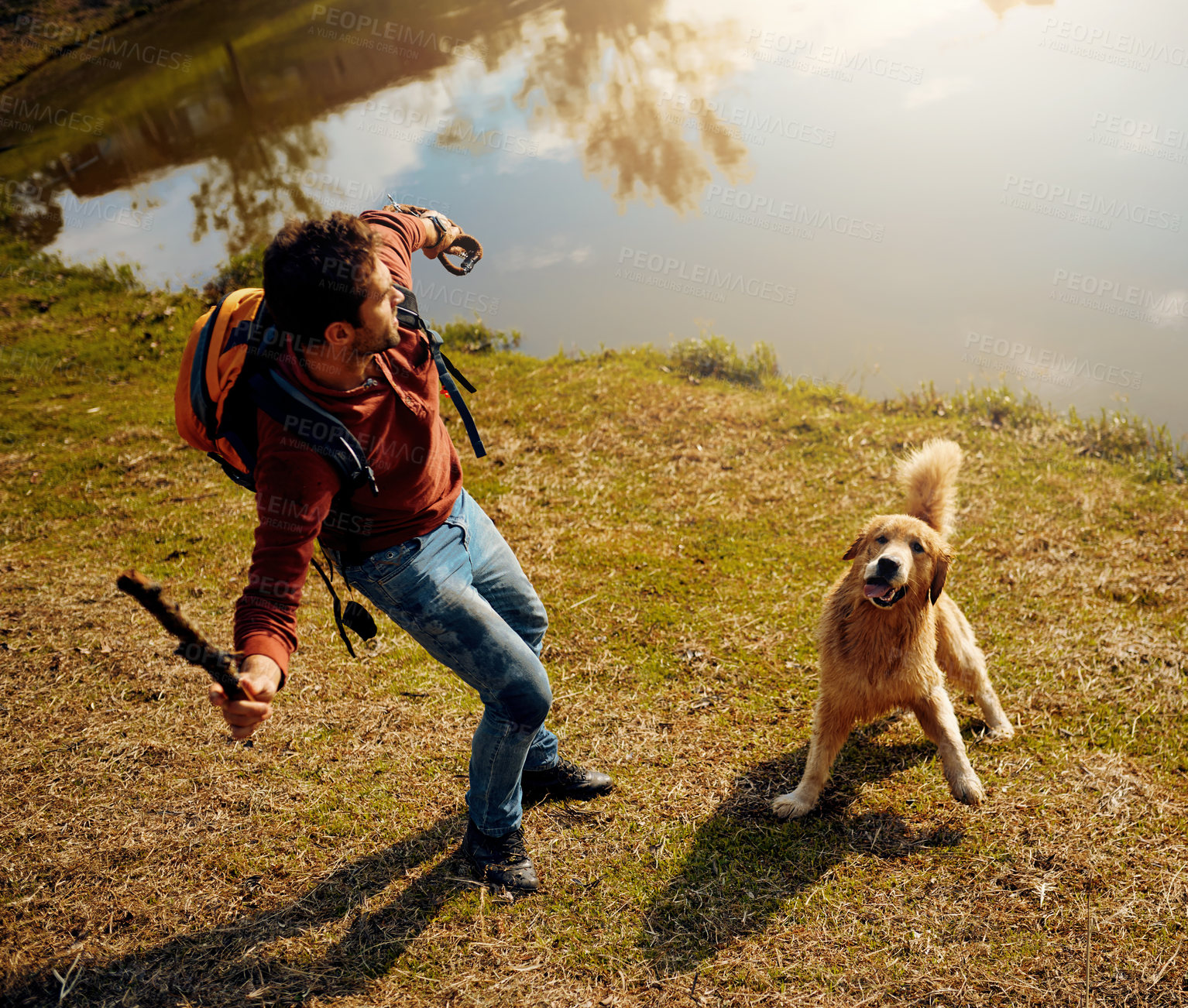 Buy stock photo Full length shot of a handsome young man playing fetch with his dog by a lake in the park