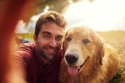 Buy stock photo Cropped shot of a handsome young man and his dog taking selfies by a lake in the park