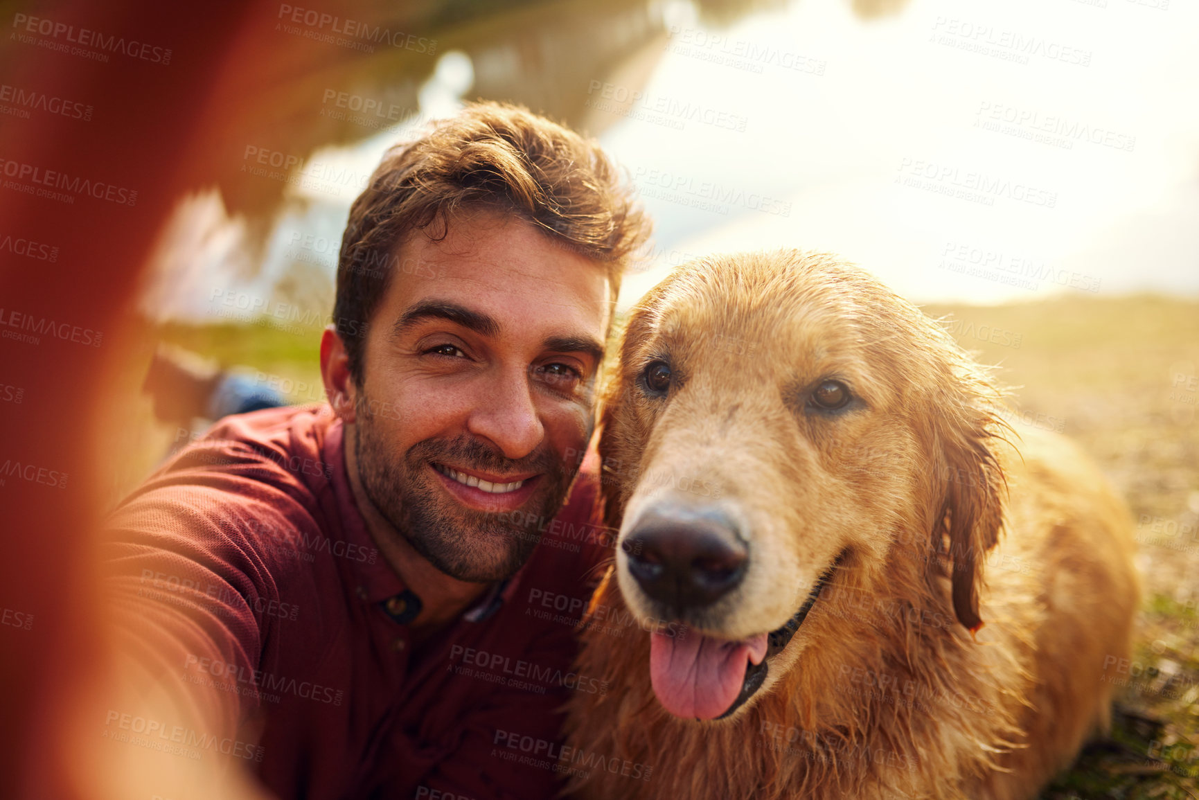 Buy stock photo Cropped shot of a handsome young man and his dog taking selfies by a lake in the park