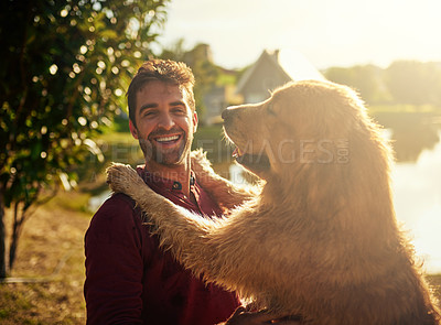 Buy stock photo Cropped portrait of a handsome young man and his dog spending the day by a lake in the park