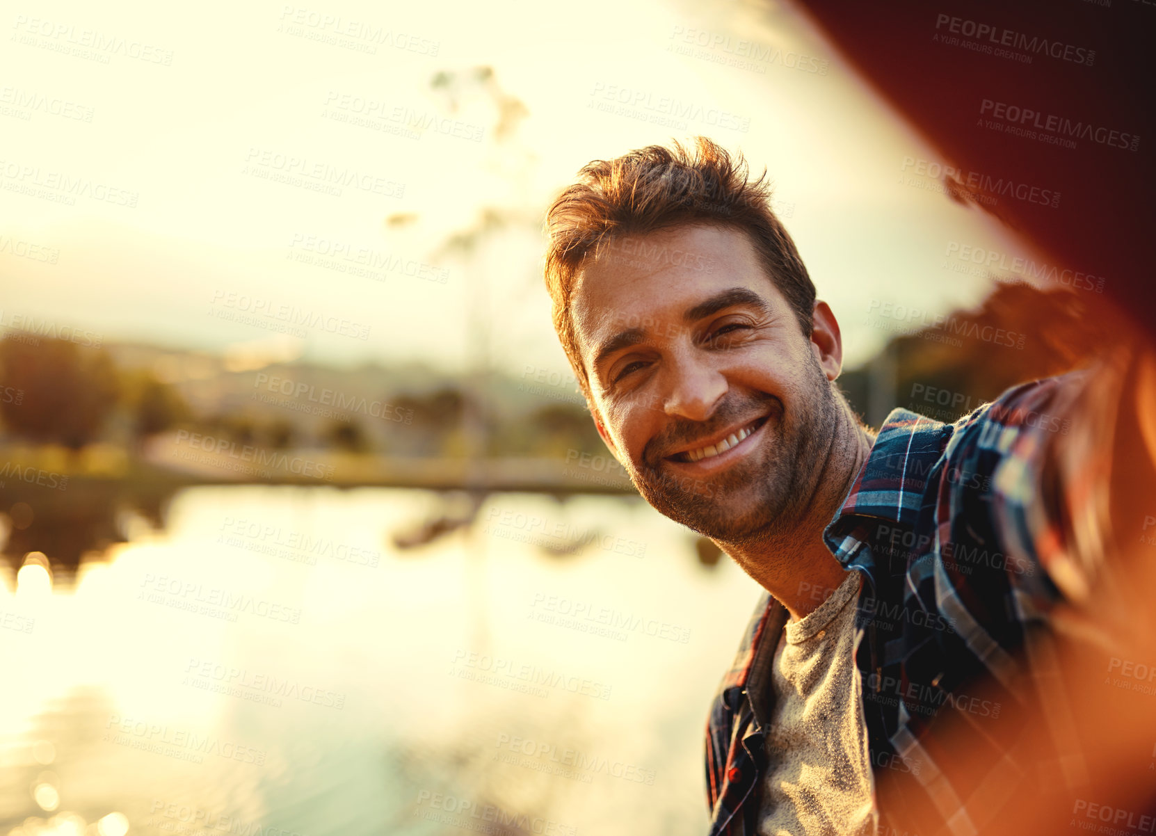 Buy stock photo Cropped portrait of a handsome young man taking selfies while spending the day at a lake