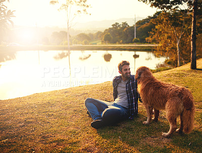 Buy stock photo Full length shot of a handsome young man and his dog spending a day by a lake in the park