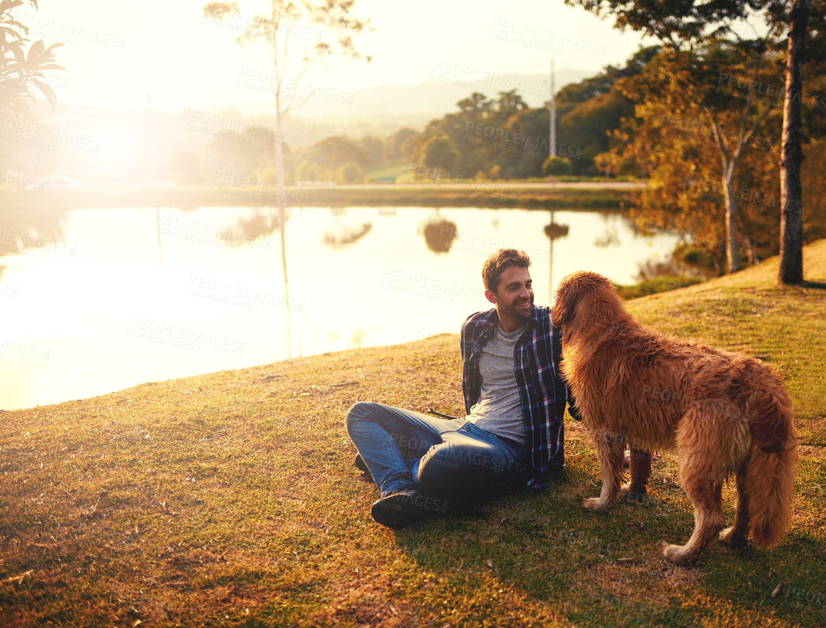 Buy stock photo Full length shot of a handsome young man and his dog spending a day by a lake in the park
