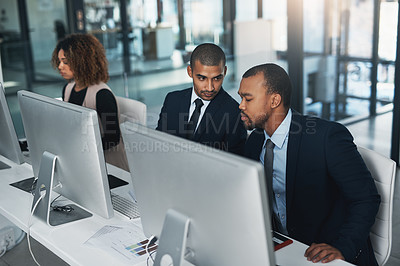 Buy stock photo High angle shot of three corporate businesspeople working on their computers in the office