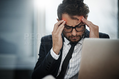 Buy stock photo Shot of a young businessman suffering with a headache while working in an office