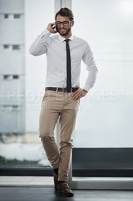 Buy stock photo Shot of a young businessman talking on a cellphone in an office