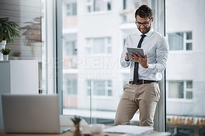 Buy stock photo Shot of a young businessman using a digital tablet in an office