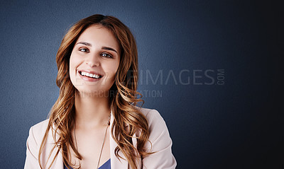 Buy stock photo Studio portrait of an attractive and confident young businesswoman posing against a dark blue background