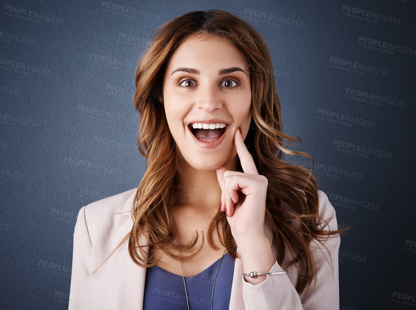 Buy stock photo Studio portrait of an attractive young businesswoman looking surprised against a dark blue background