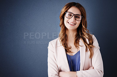 Buy stock photo Studio portrait of an attractive and confident young businesswoman posing against a dark blue background