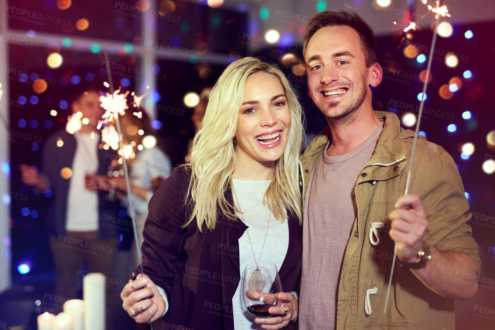Buy stock photo Portrait of an attractive young couple having fun with sparklers at a nightclub