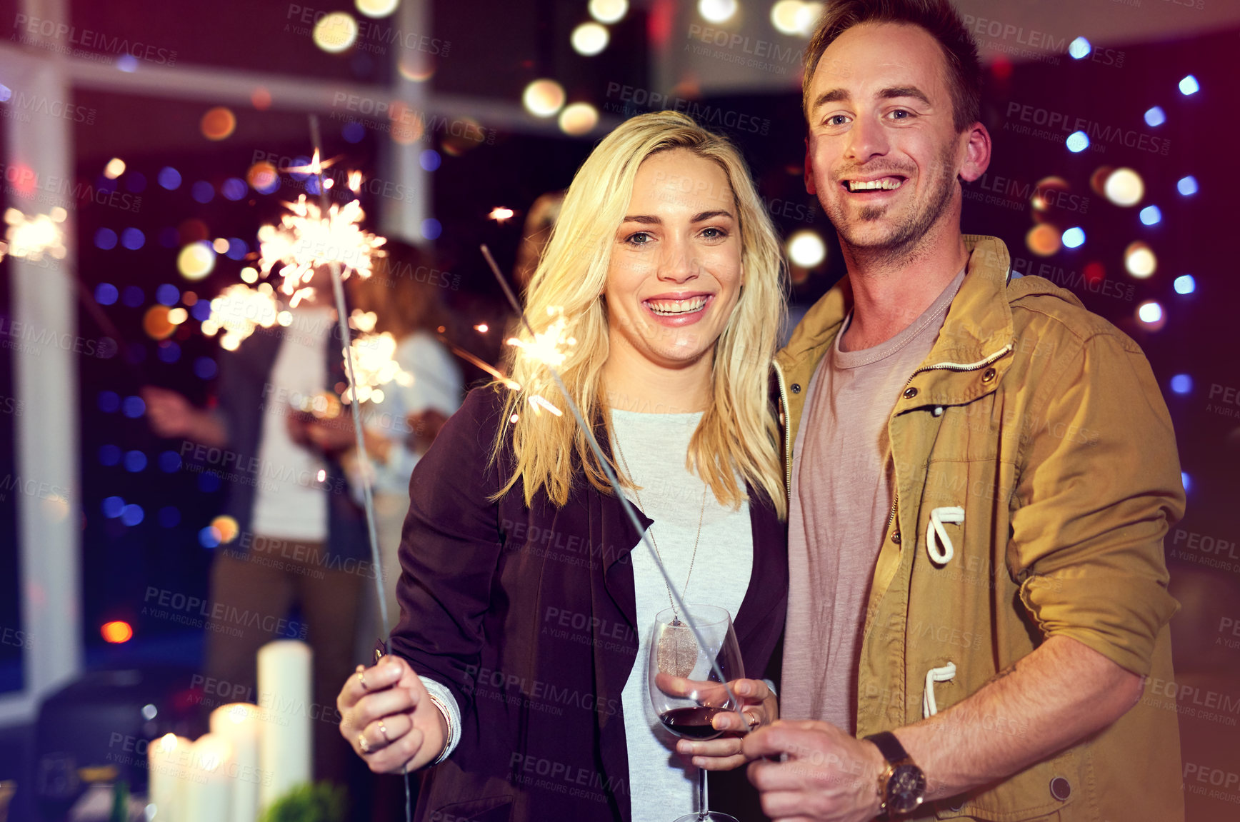 Buy stock photo Portrait of an attractive young couple having fun with sparklers at a nightclub