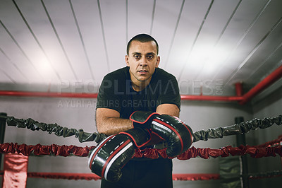 Buy stock photo Portrait of a confident young male boxer leaning against ropes inside of a boxing ring at a gym during the day