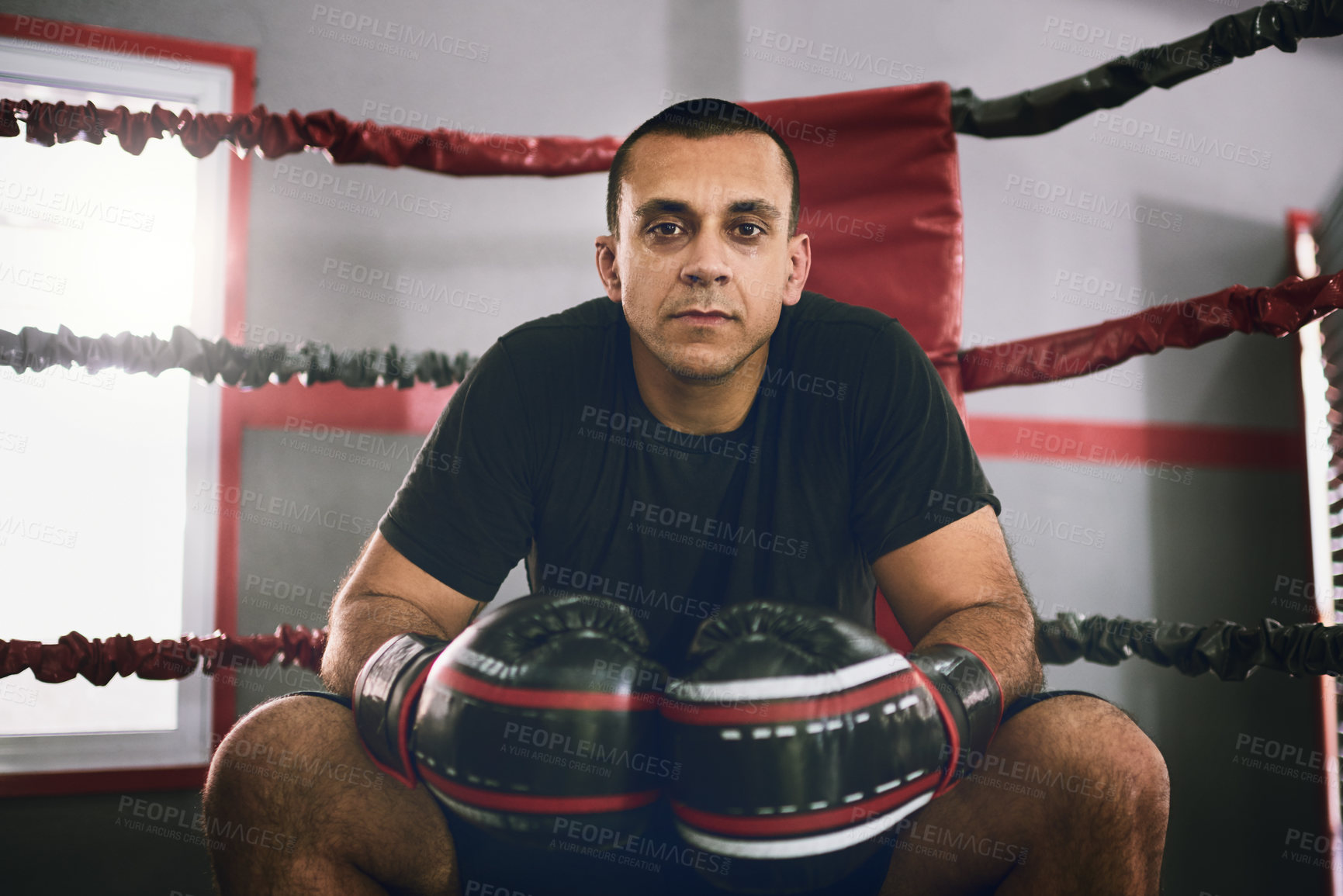 Buy stock photo Portrait of a confident young male boxer seated in the corner of a boxing ring at a gym during the day