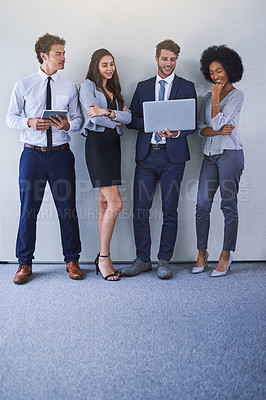 Buy stock photo Shot of a diverse group of businesspeople using wireless technology while standing against a grey background