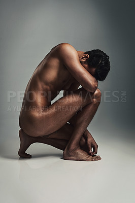 Buy stock photo Studio shot of a handsome young man crouching in the nude against a grey background
