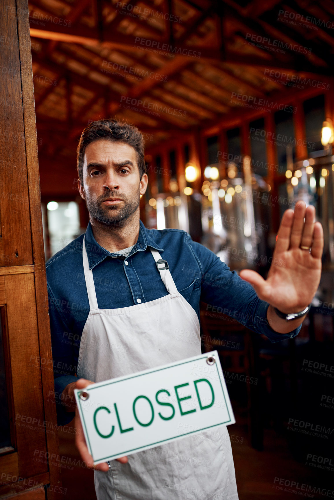 Buy stock photo Portrait of a serious looking young business owner holding up a sign saying 