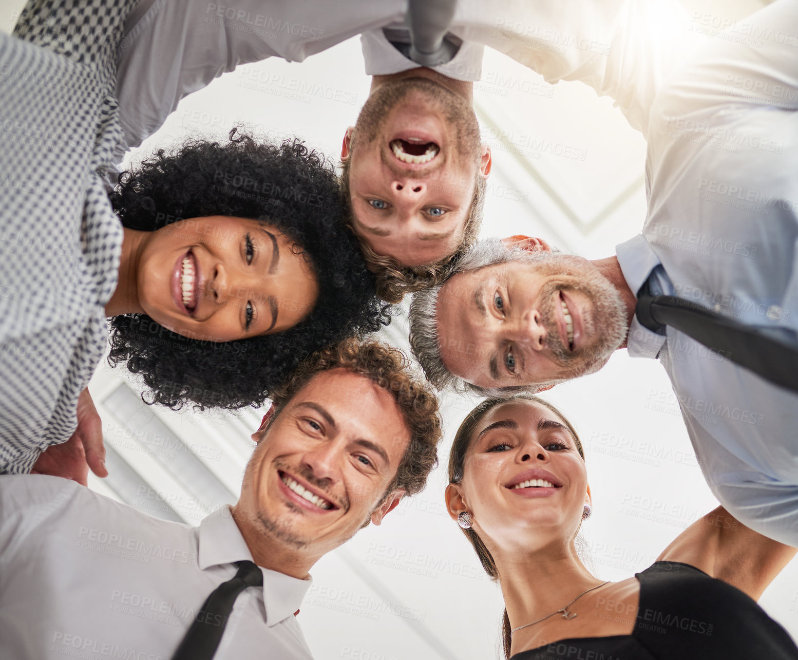 Buy stock photo Low angle portrait of a group of businesspeople huddled together in solidarity