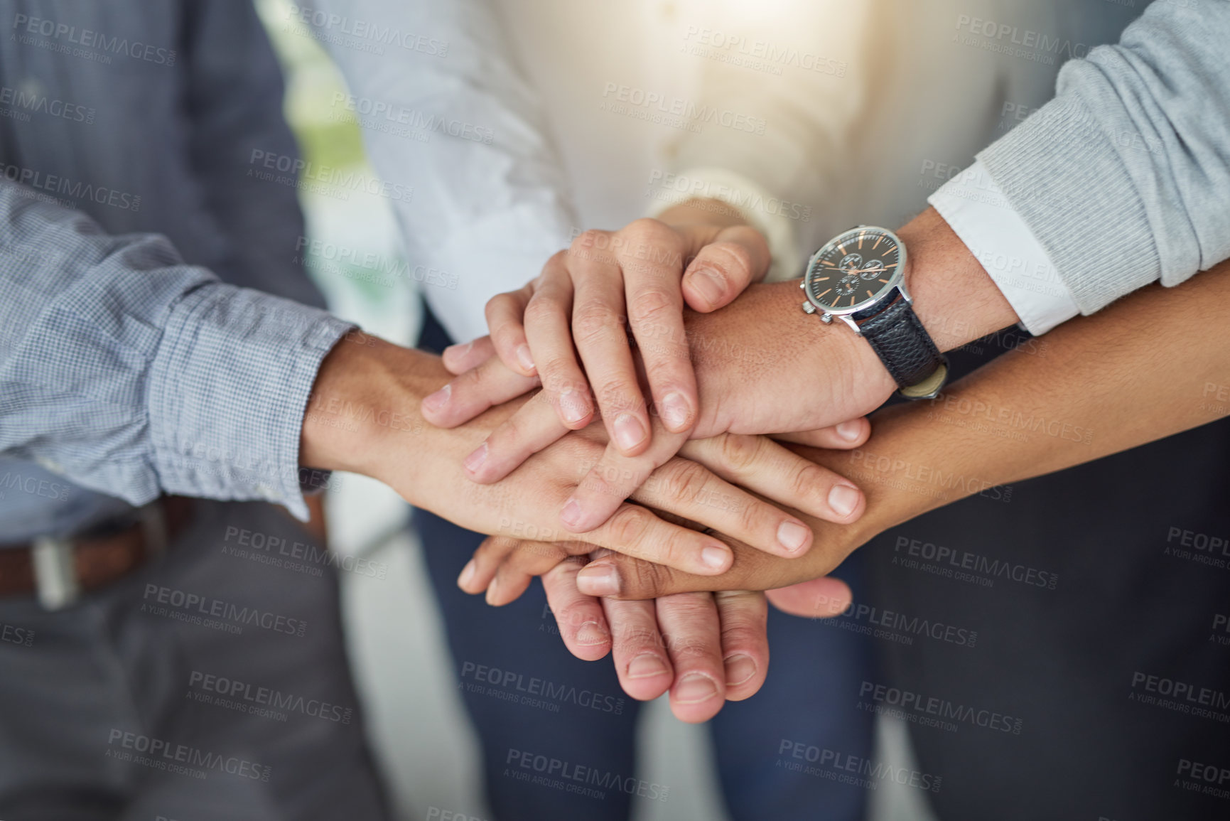 Buy stock photo Cropped shot of a group of colleagues joining hands in solidarity in a modern office