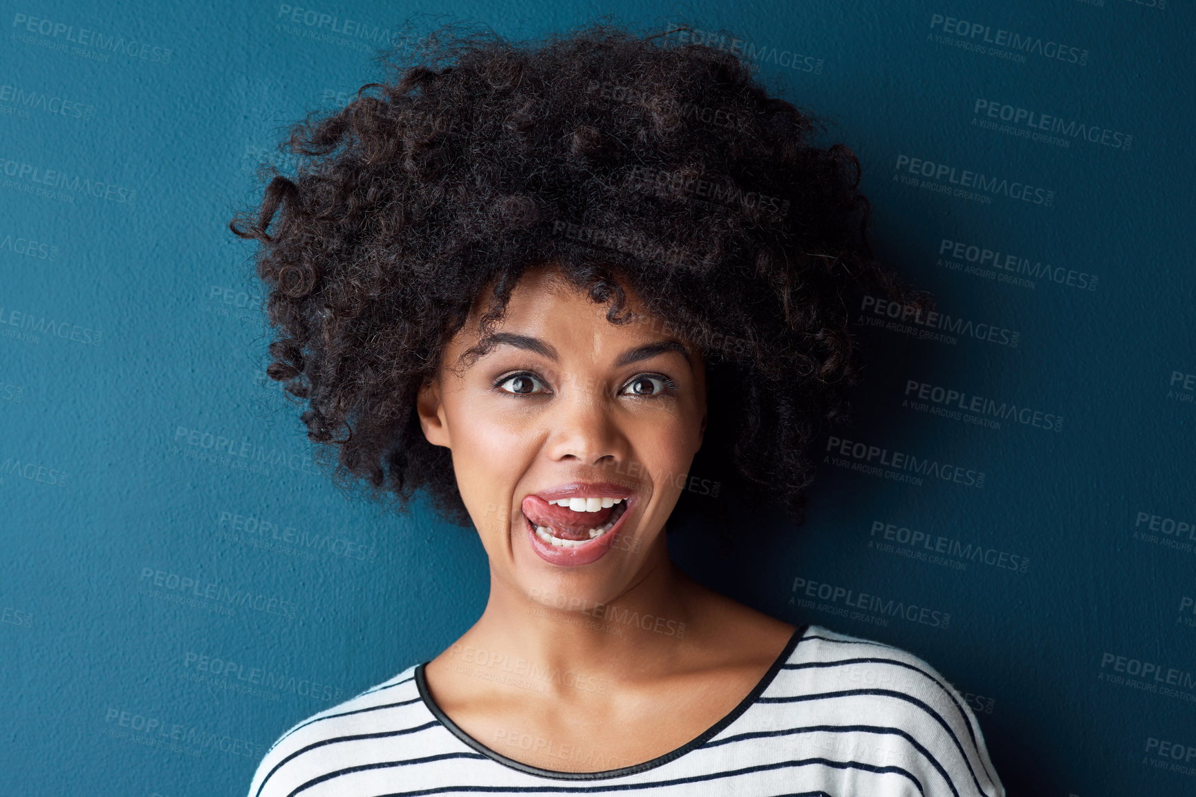 Buy stock photo Studio portrait of an attractive young woman sticking her tongue out against a blue background