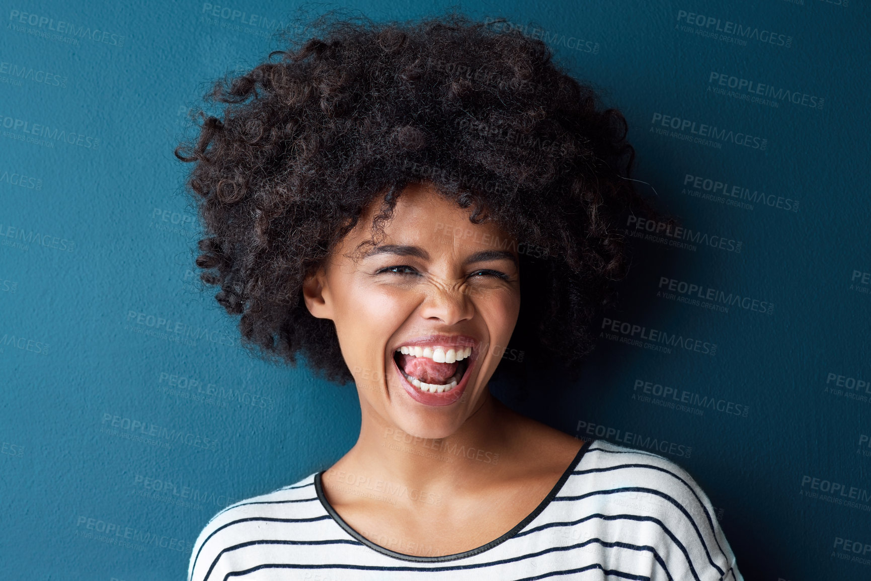 Buy stock photo Portrait, funny and woman with tongue out, silly and happiness against a blue studio background. Face, female person and model with facial expression, humor and comic with joy, smile and goofy girl