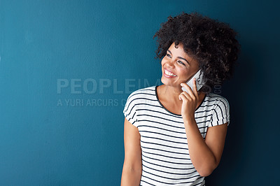 Buy stock photo Studio shot of an attractive young woman talking on a cellphone against a blue background