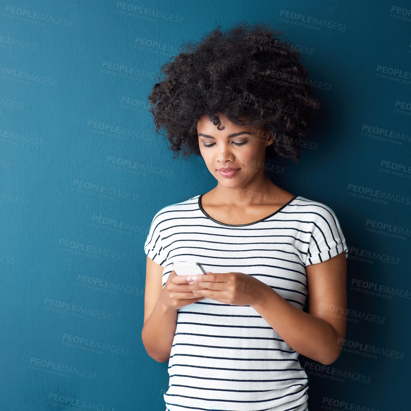 Buy stock photo Studio shot of an attractive young woman using a cellphone against a blue background