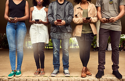 Buy stock photo Cropped shot of a group of unrecognizable people using cellphones in a public park