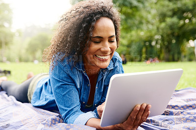 Buy stock photo Cropped shot of a beautiful young woman using a tablet in a public park