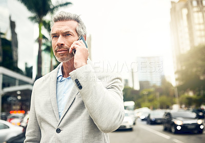 Buy stock photo Shot of a mature businessman talking on a cellphone in the city